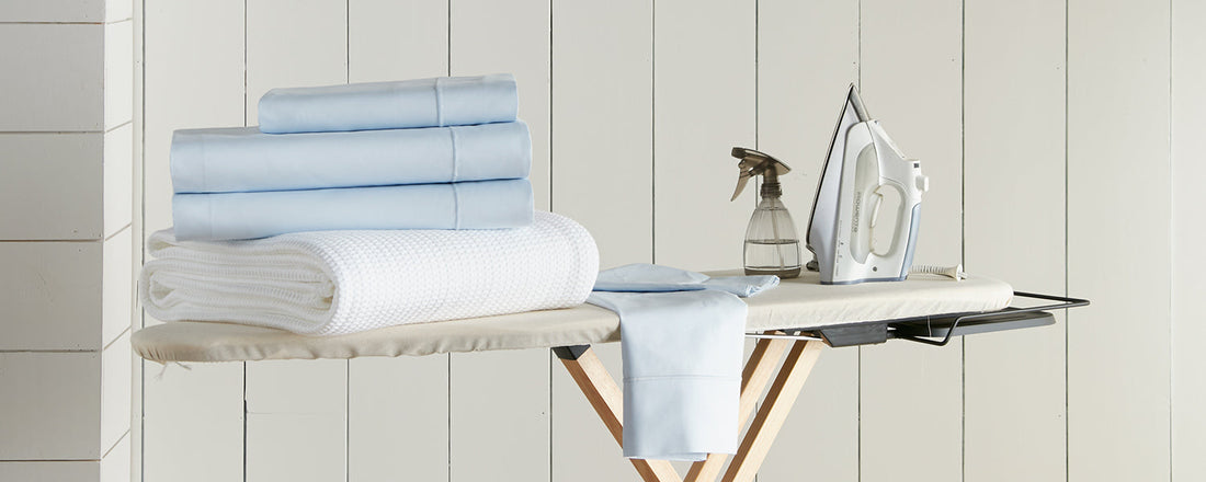 sheets and bedding on ironing board with iron