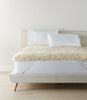 Wool mattress topper with elastic straps on bed