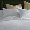 Harper white duvet and shams on bed brass framed headboard